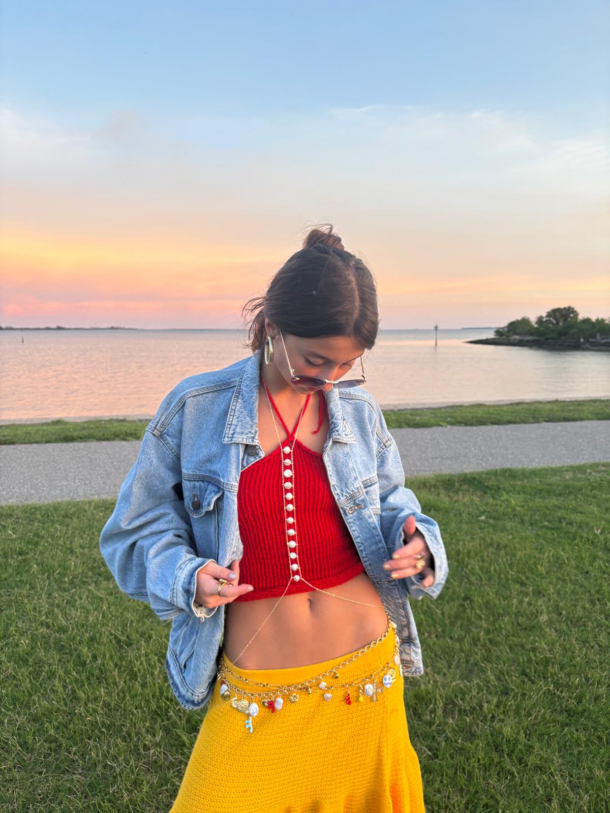 Woman wearing La Perla natural coin pearl body chain in gold-filled, vertical pearl line down chest, sunset background