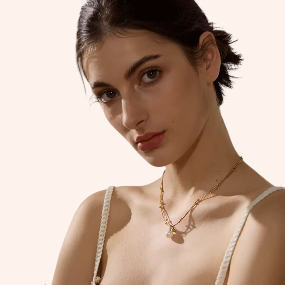Model wearing the Iris Pearl Gold Necklace by Mannaz Designs — triple-strand gold chain with pearl charm.